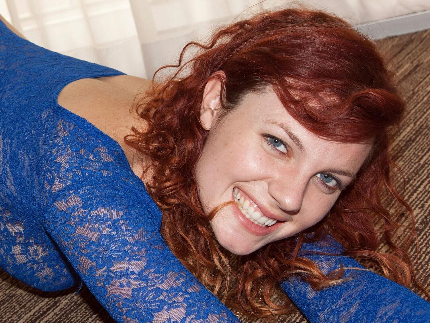 Redhead in blue blodysuit posing on balcony